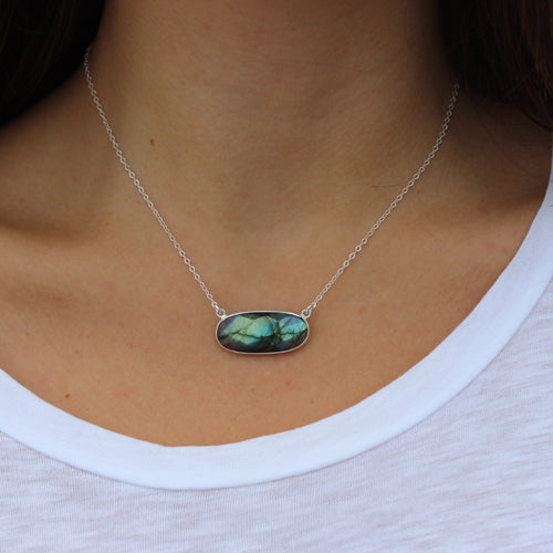 labradorite is a iridescent stone of blue, green and gray hues. from Margie Edwards Jewelry. Shown on a model with a white tee shirt. 