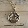 Reversible gold coin pendant featuring a radiant rising sun design